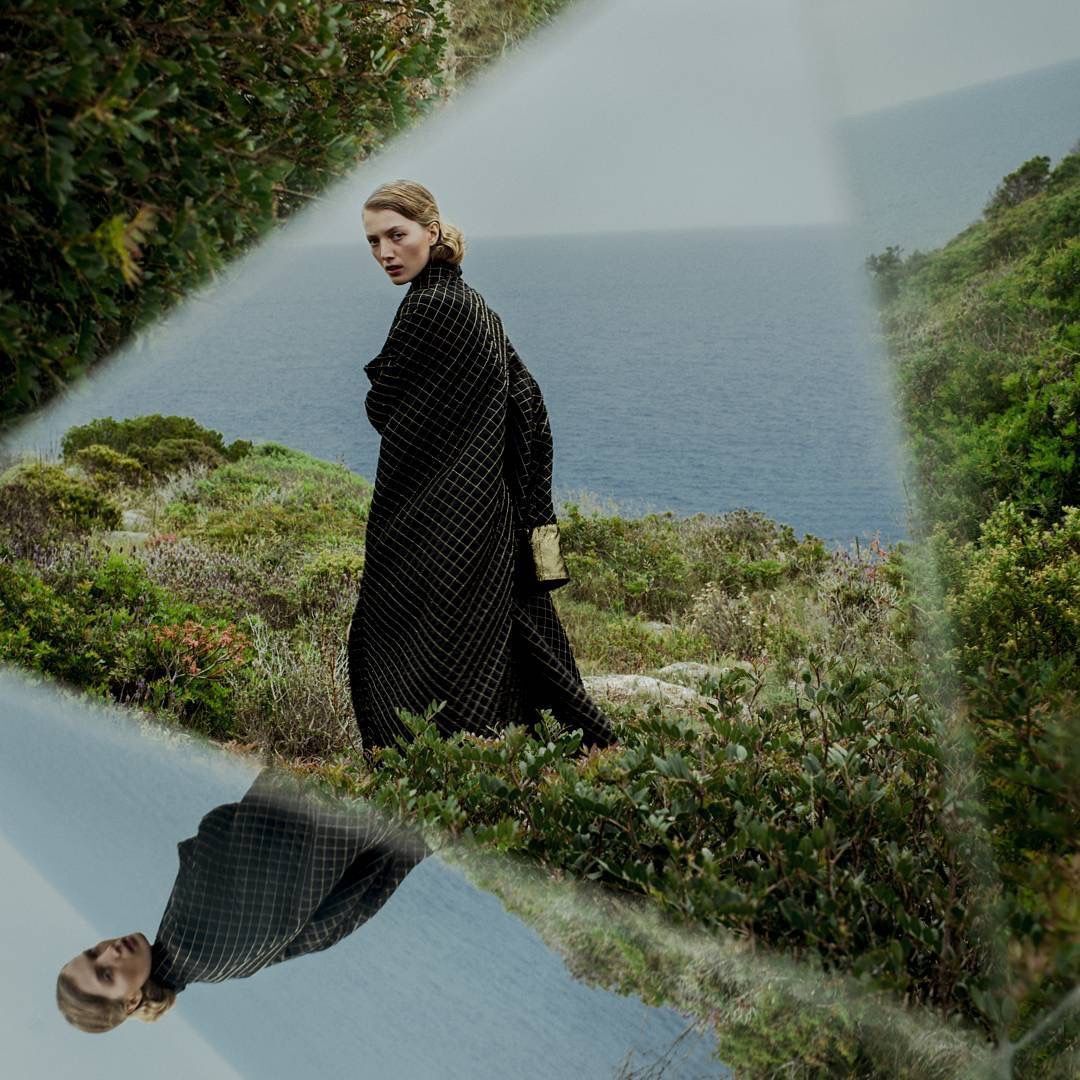 A person in a green landscape reflected in a mirror